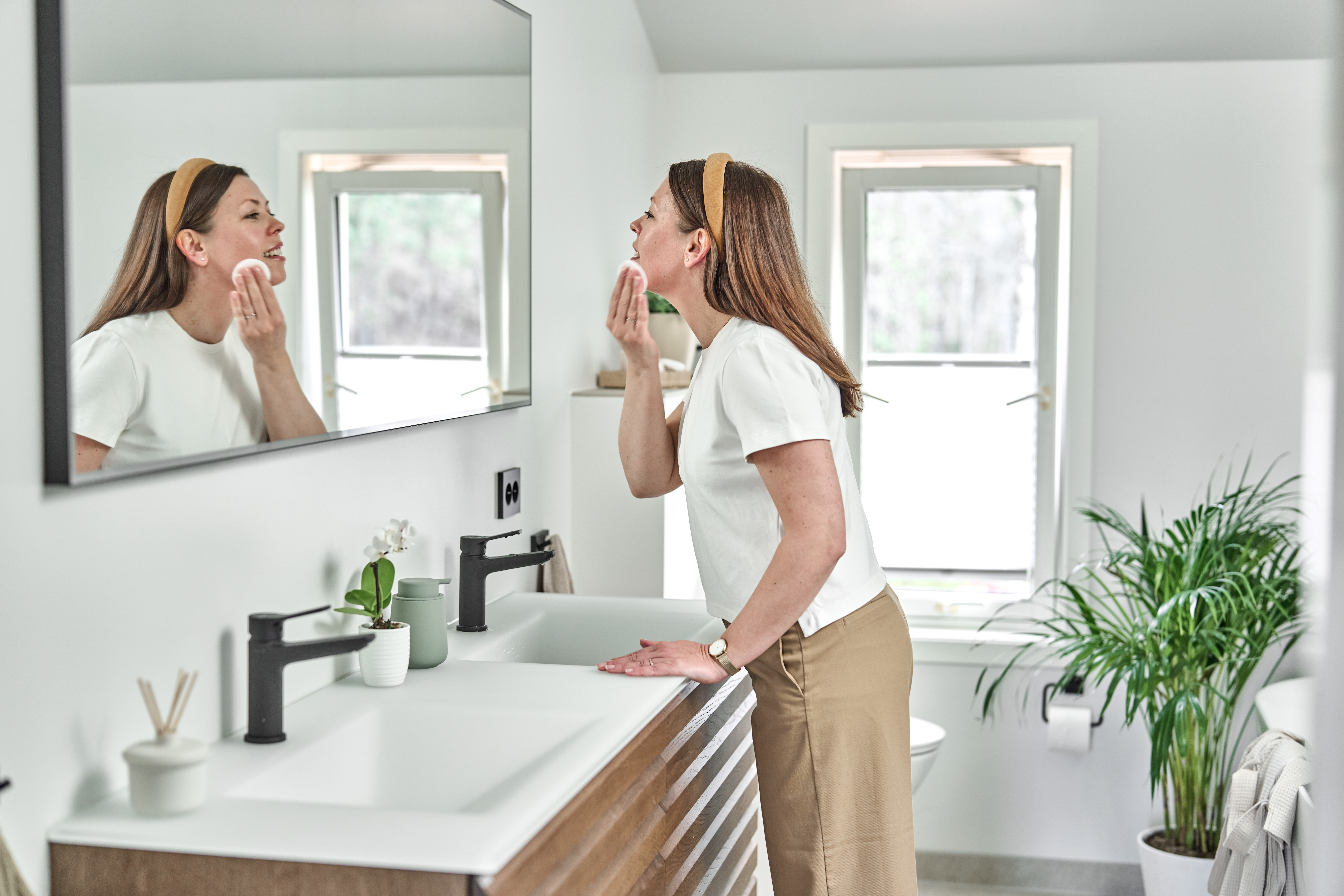 Dame står foran et speil på badet.